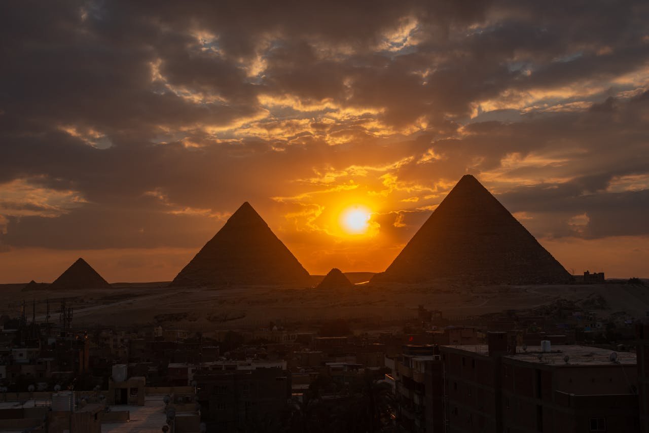 Silhouette of the Giza pyramids at sunset, capturing dramatic skies and ancient wonder.